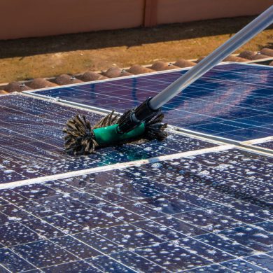 solar-worker-cleaning-photovoltaic-panels-with-brush-and-water-photovoltaic-cleaning-scaled-1